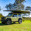 small rooftop tent attached to car sitting in grass field
