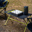 camping table holding a bluetooth speaker and game of naughts and crosses