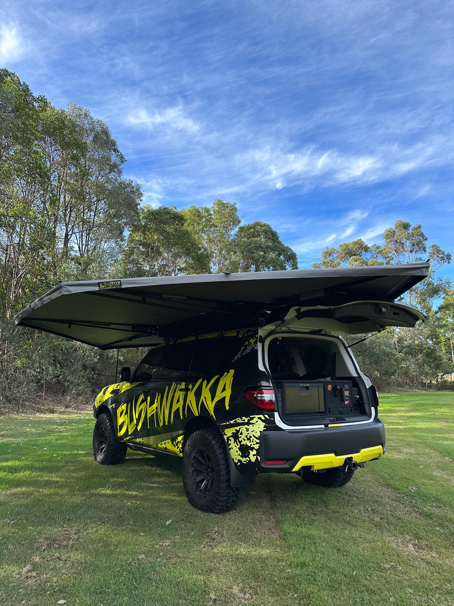 hardshell rooftop tent on black car with bushwakka branding with its boot open